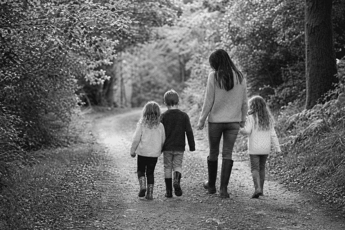 Babysitter walking with children along a woodland path